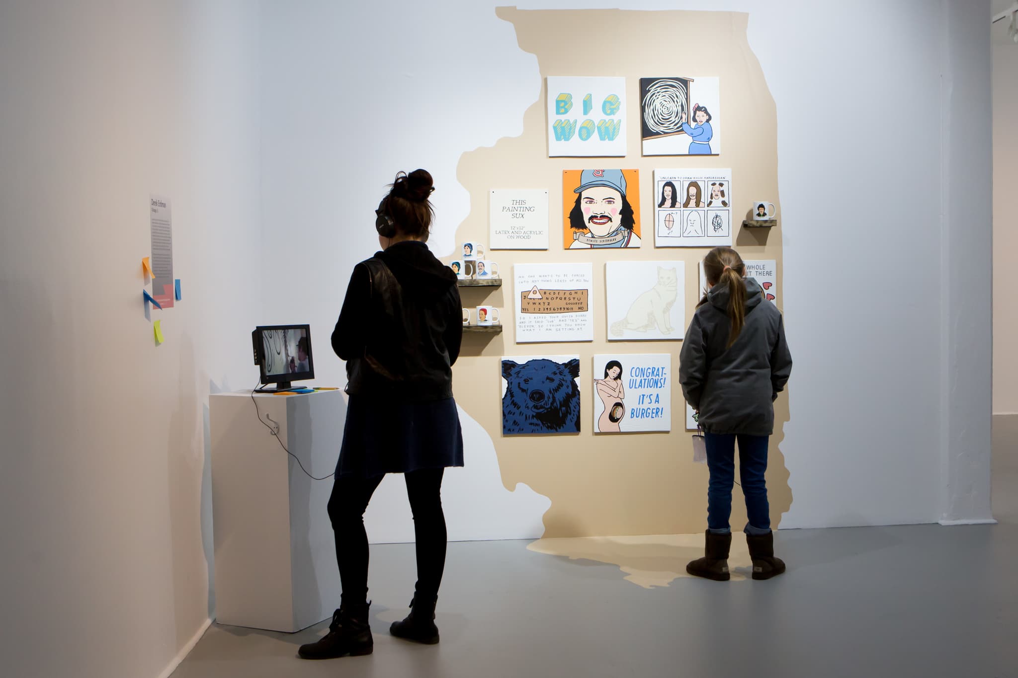 Two visitors at the Mills Gallery look at different works on view.