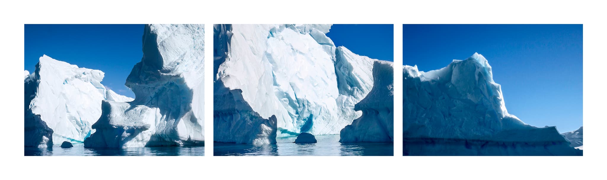A series of icebergs in the ocean, emerging against a blue sky.