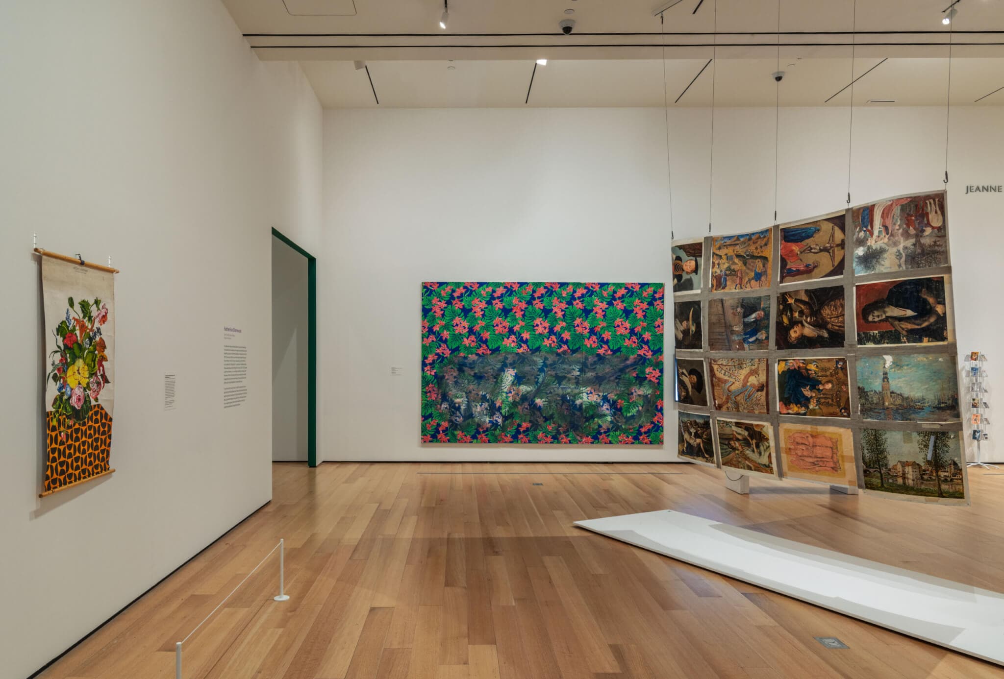 An installation view of an exhibition shows a hanging artwork and two wall-mounted mixed media works.